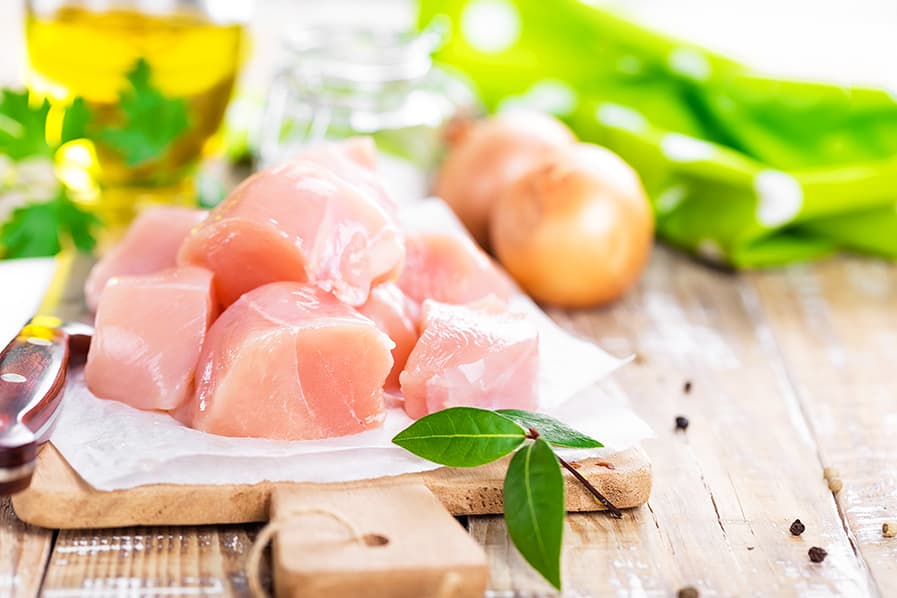 Peito de frango cortado em cubos sobre tábua de madeira