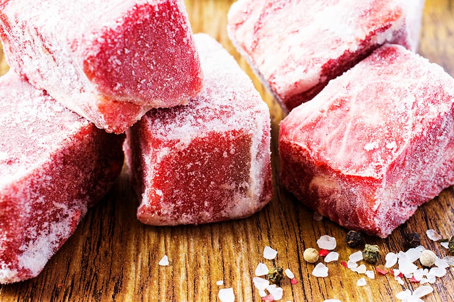 Cubos de carne vermelha congelada ao lado de sal grosso