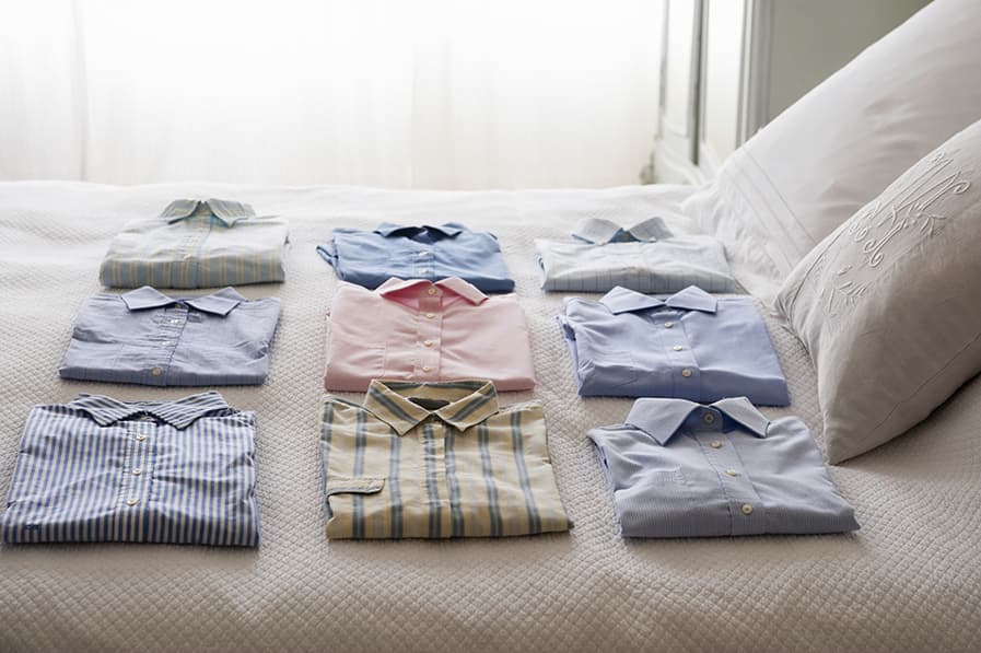 Camisas dobradas de forma alinhada sobre o colchão da cama