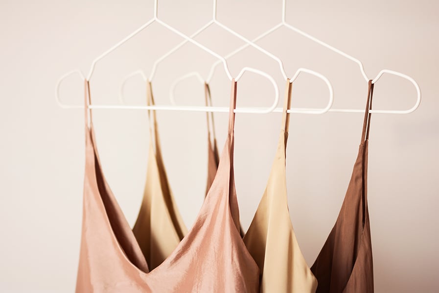 Roupas de tecidos delicados em cabides brancos