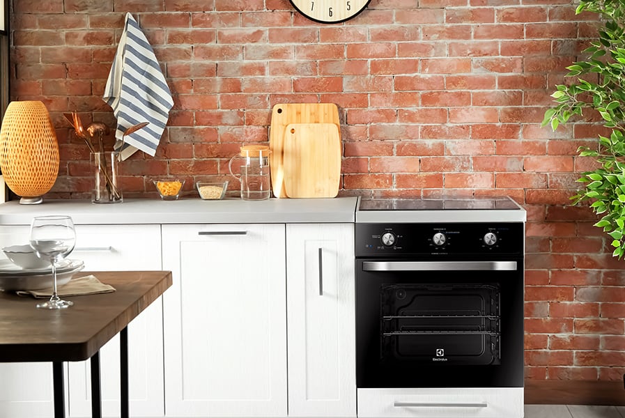 Cozinha decorada com móveis diversos e forno de embutir.