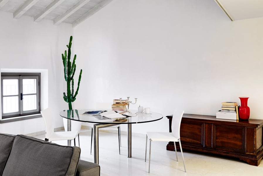 Sala com mesa redonda com tampo de vidro e cadeiras brancas