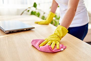 Mulher limpa móvel de madeira com pano úmido