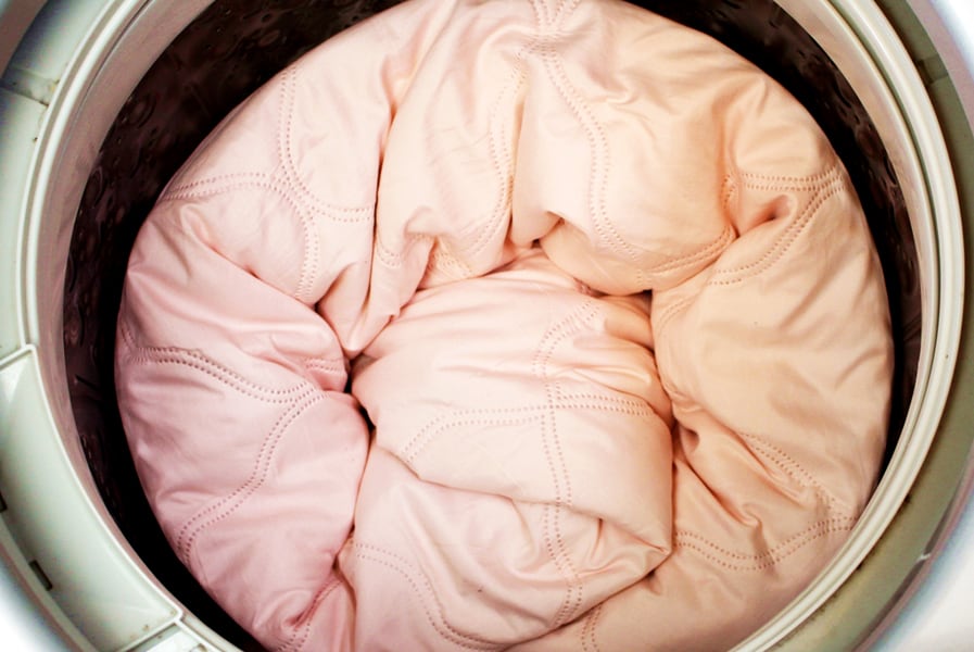 Roupa de cama na parte interna da maquina de lavar